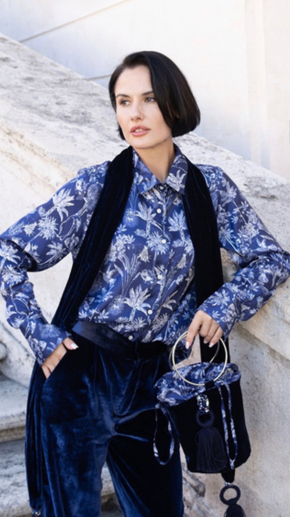Sciarpa Eterna in velluto di seta blu con nappine gioiello indossata da una modella elegante.
