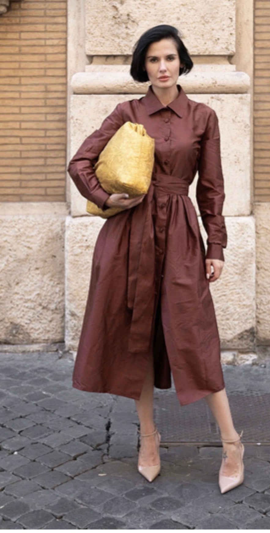Sofia Marrone in abito in shantung elegante con accessorio dorato, sfila in strada