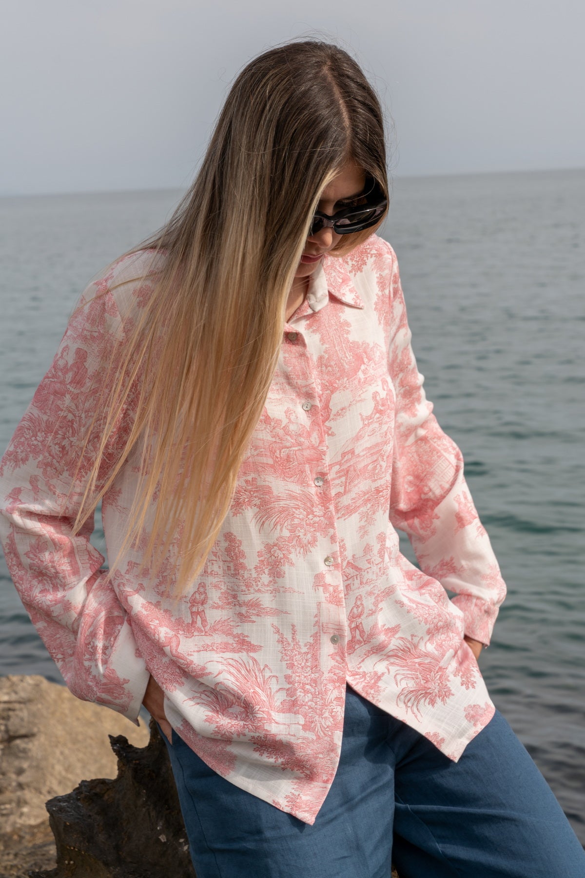Camicia Elisabeth in Toile de Jouy rosa indossata da una donna elegante sullo sfondo del mare, perfetta per estate26.