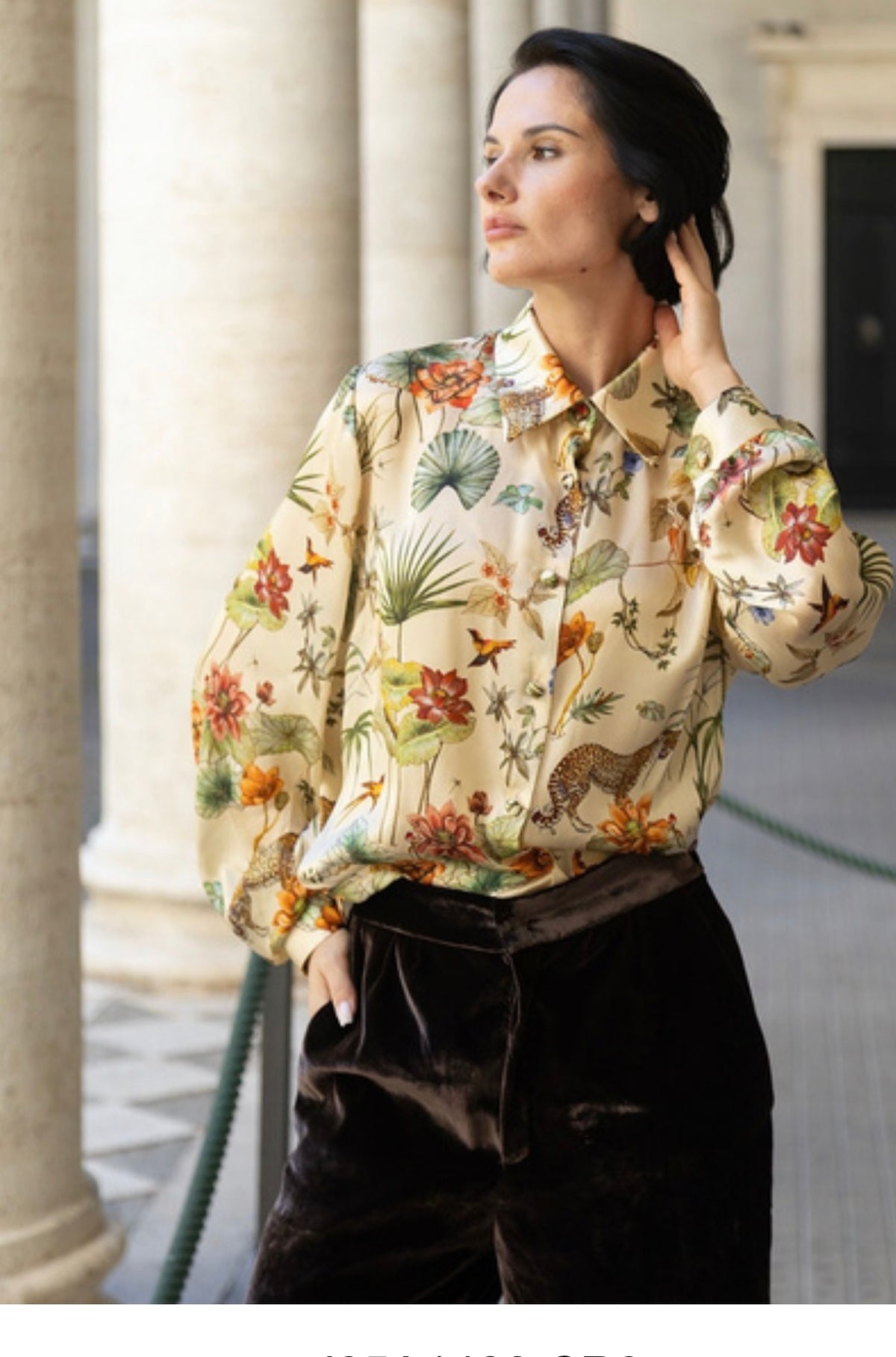 Camicia in seta avorio con stampa botanica indossata da donna elegante in contesto architettonico.