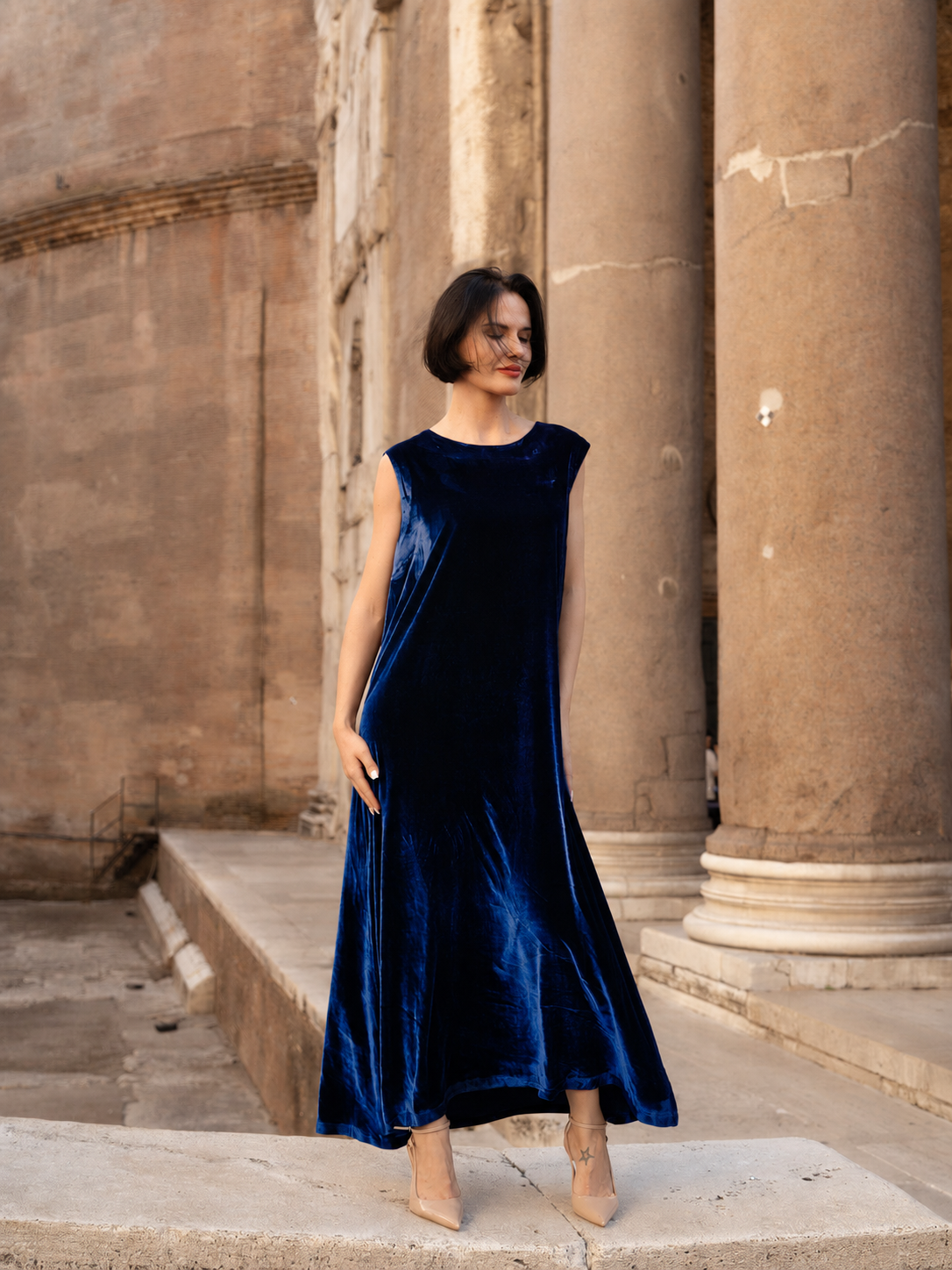Modella che indossa abito lungo velluto seta elegante in un contesto storico.