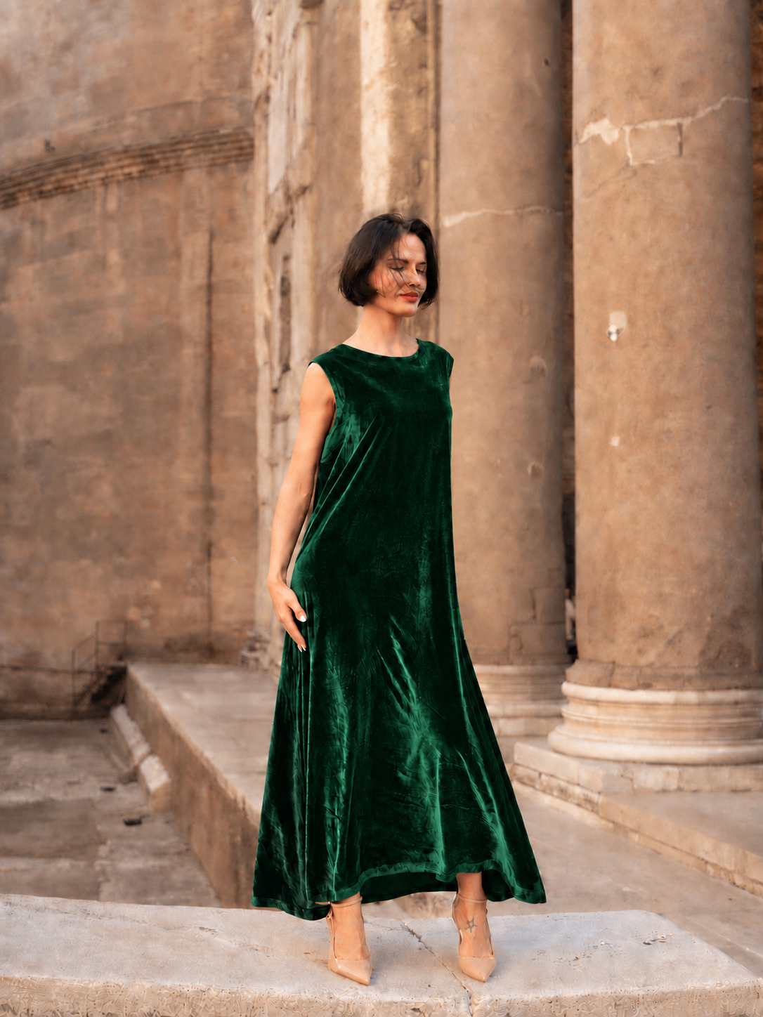Abito lungo in velluto di seta verde indossato da una donna in un contesto elegante e storico.