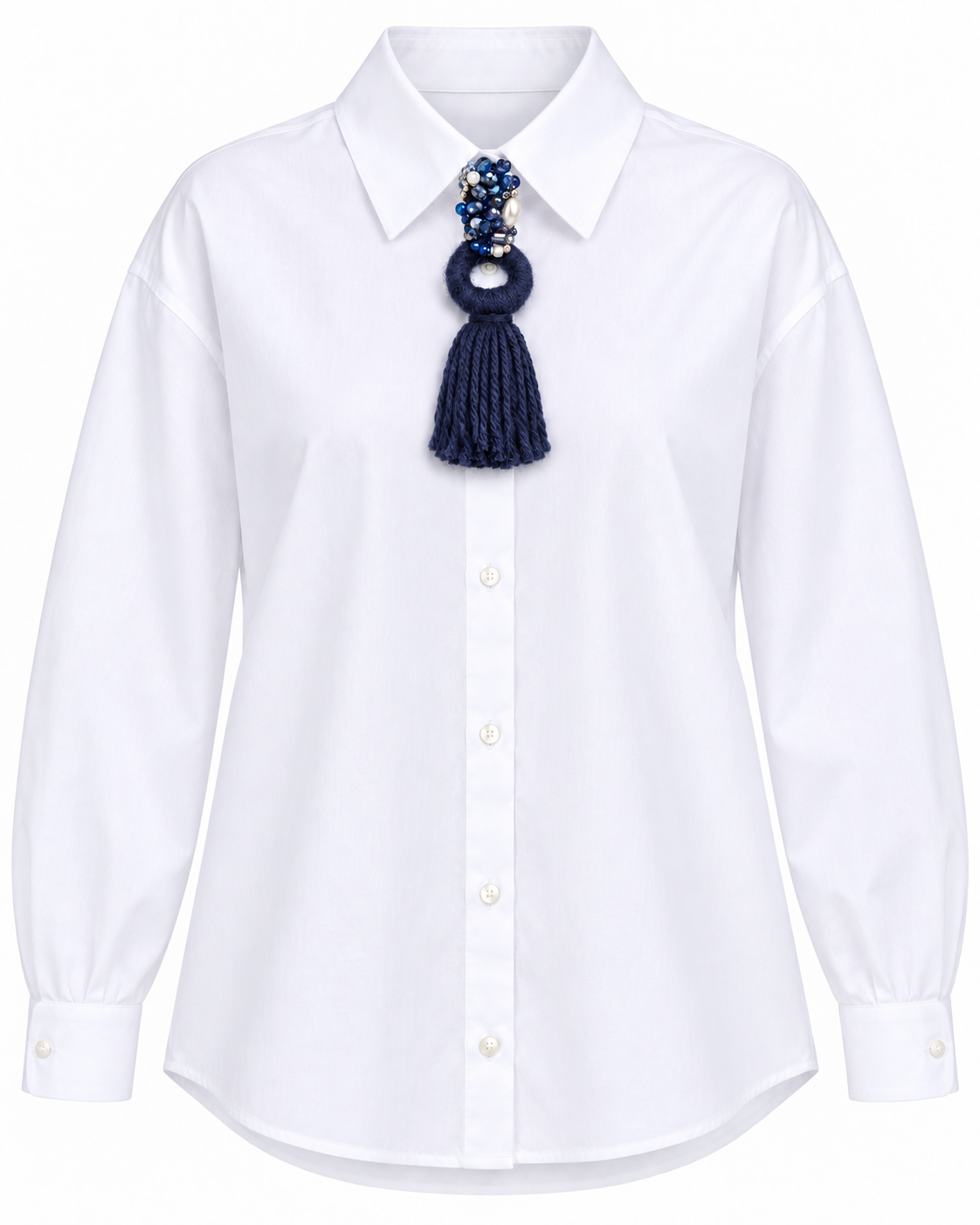 Spilla gioiello con nappina in lana blu applicata su camicia bianca elegante.
