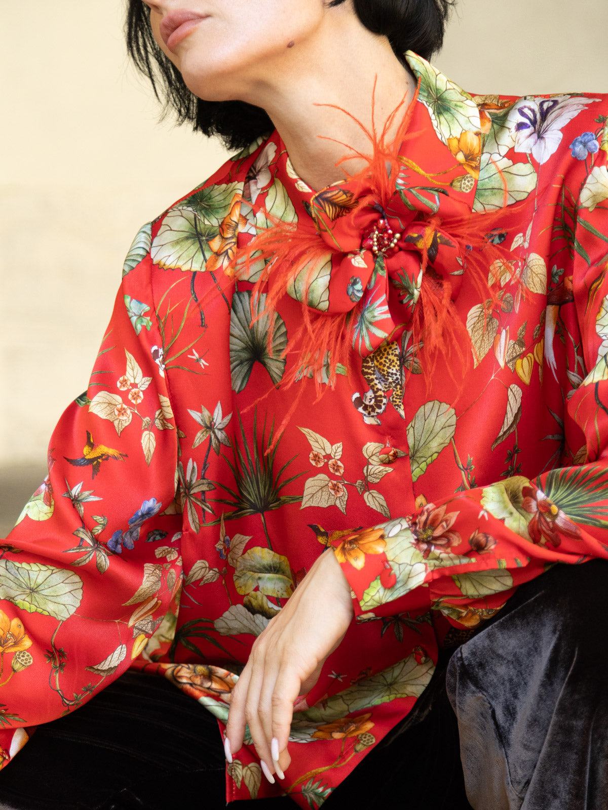 Spilla horti romana in seta indossata su camicia rossa floreale, dettaglio elegante e scenografico.