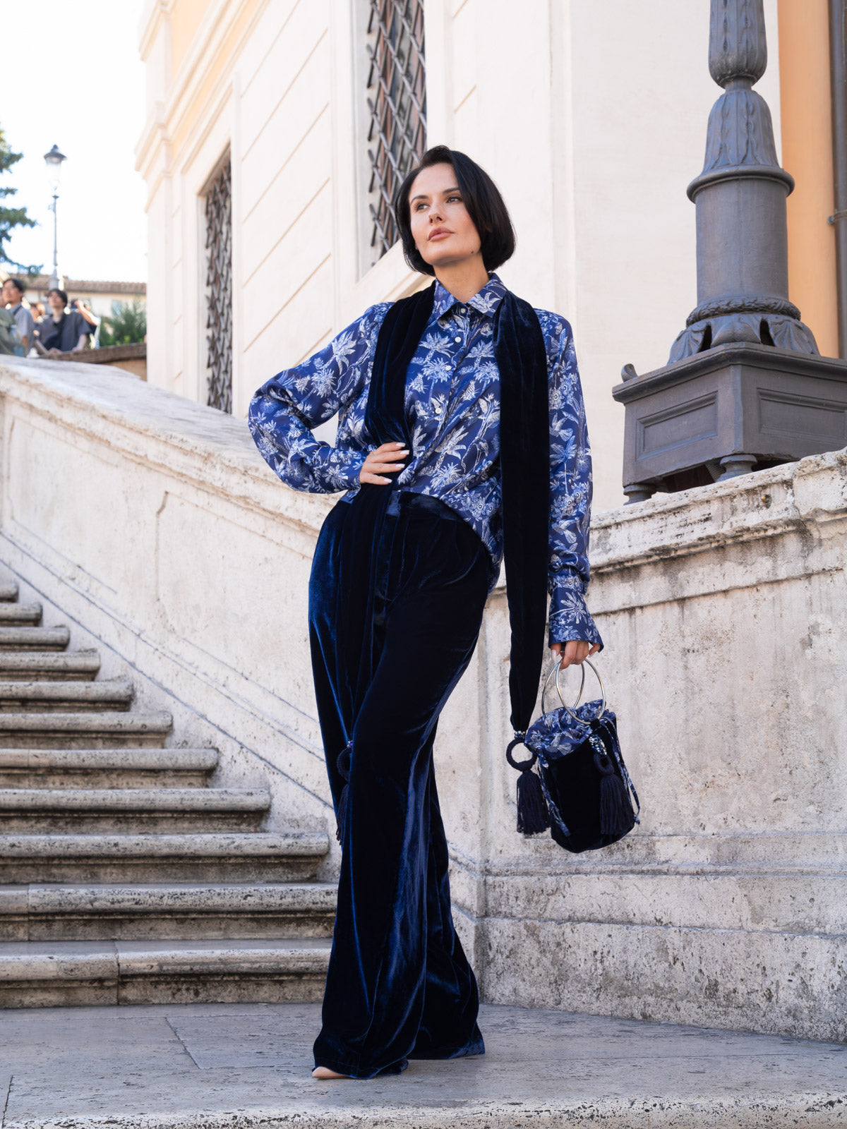 Modella che indossa la camicia viscosa Liberty con pantaloni in velluto blu, sullo sfondo di una scalinata elegante.
