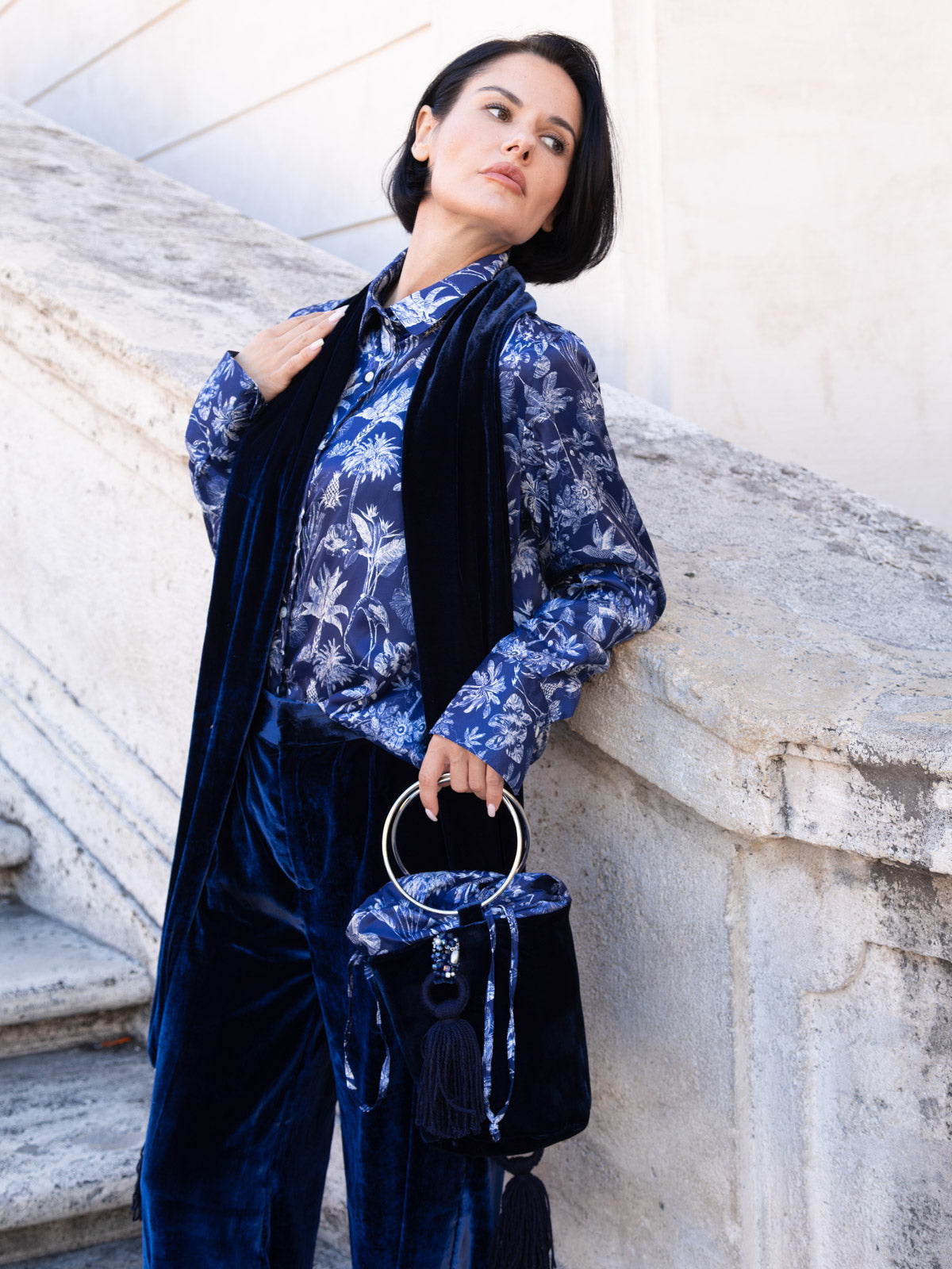 Camicia viscosa Liberty indossata con pantaloni in velluto blu e borsa coordinata, in un ambiente elegante.