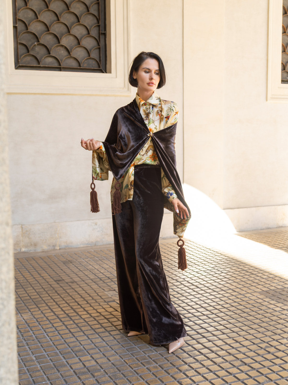 Modella che indossa la camicia in seta avorio con stampa botanica e pantaloni in velluto, in un ambiente elegante.
