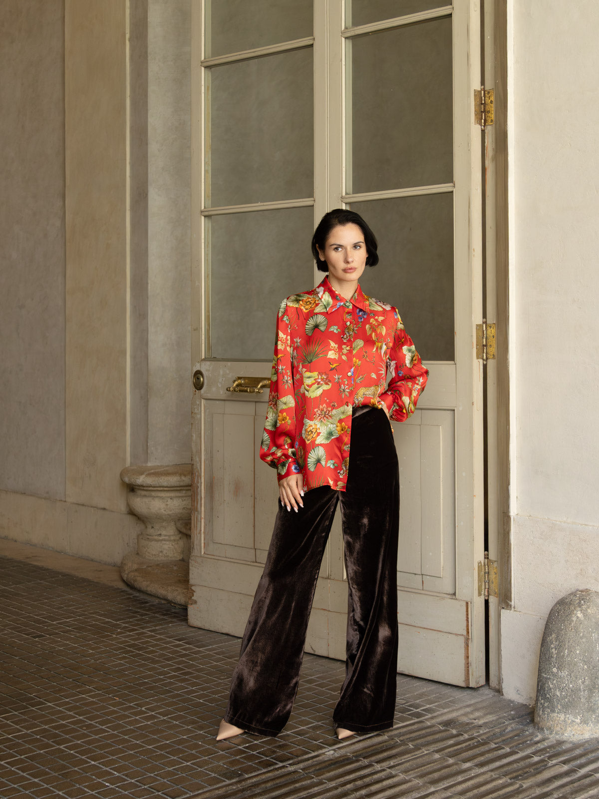 Camicia in seta rossa Horti Imperiali indossata con pantaloni in velluto, look elegante in un ambiente raffinato.