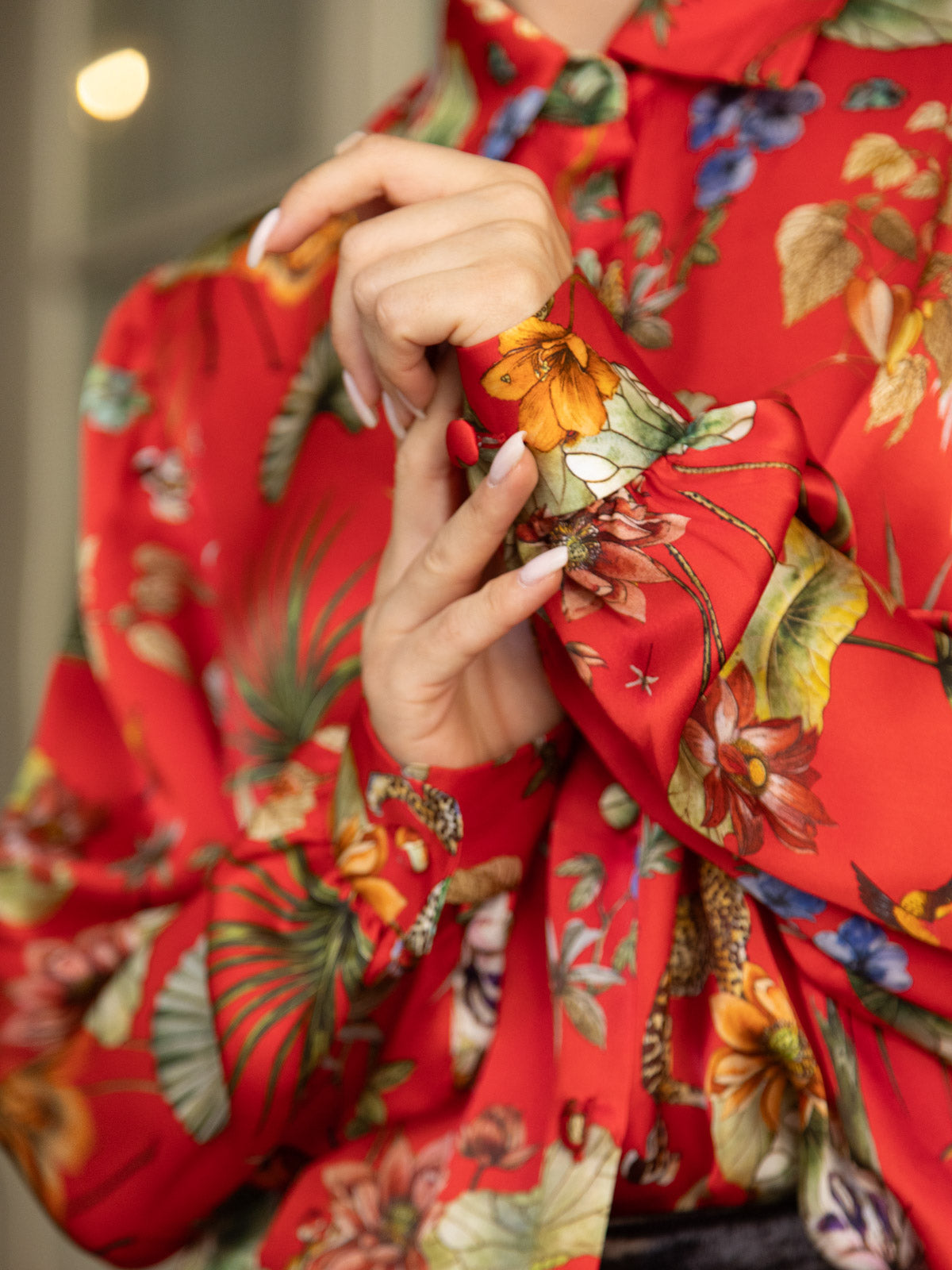 Camicia in seta rossa Horti Imperiali con stampa floreale, indossata da una persona che systematizza il polsino.