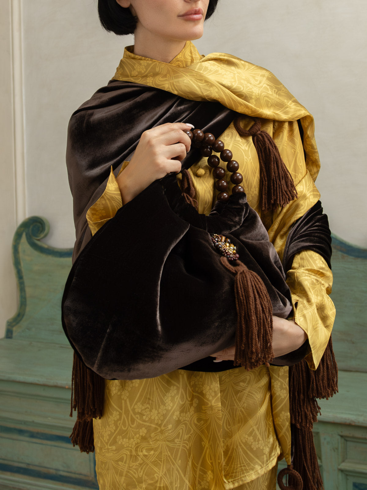 Scialle in velluto e Liberty con nappine indossato da una donna elegante, accompagnato da una borsa abbinata.