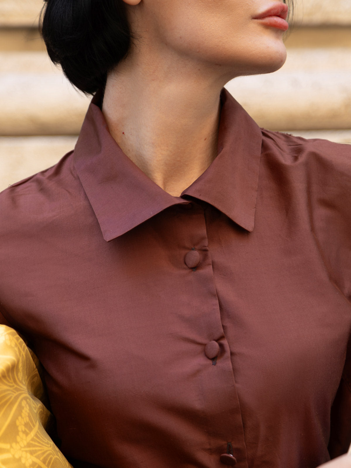 Dettaglio dell'abito in shantung elegante con collo alto e bottoni, perfetto per occasioni speciali.