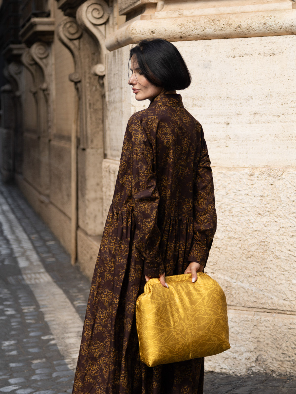Abito lungo in tessuto Liberty indossato da donna con borsa gialla in una strada storica.
