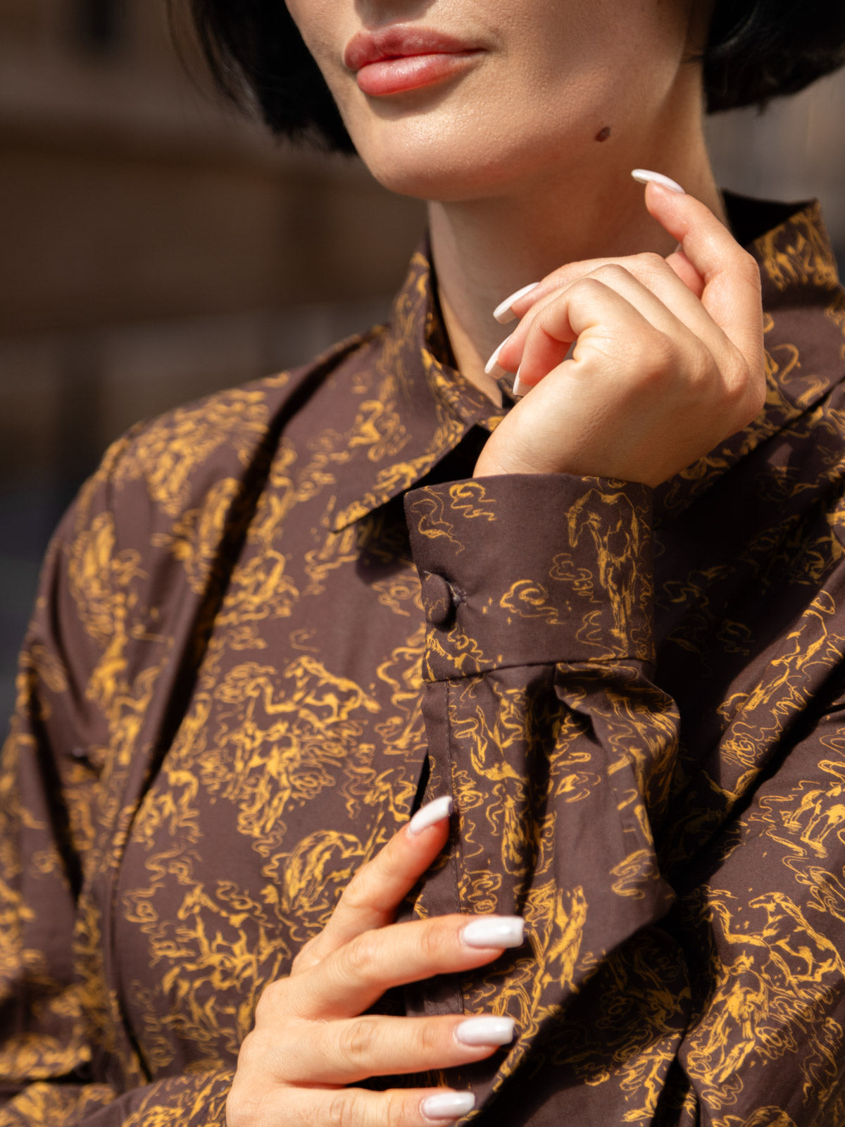Dettaglio di abito lungo in tessuto Liberty con maniche eleganti e design botanico.