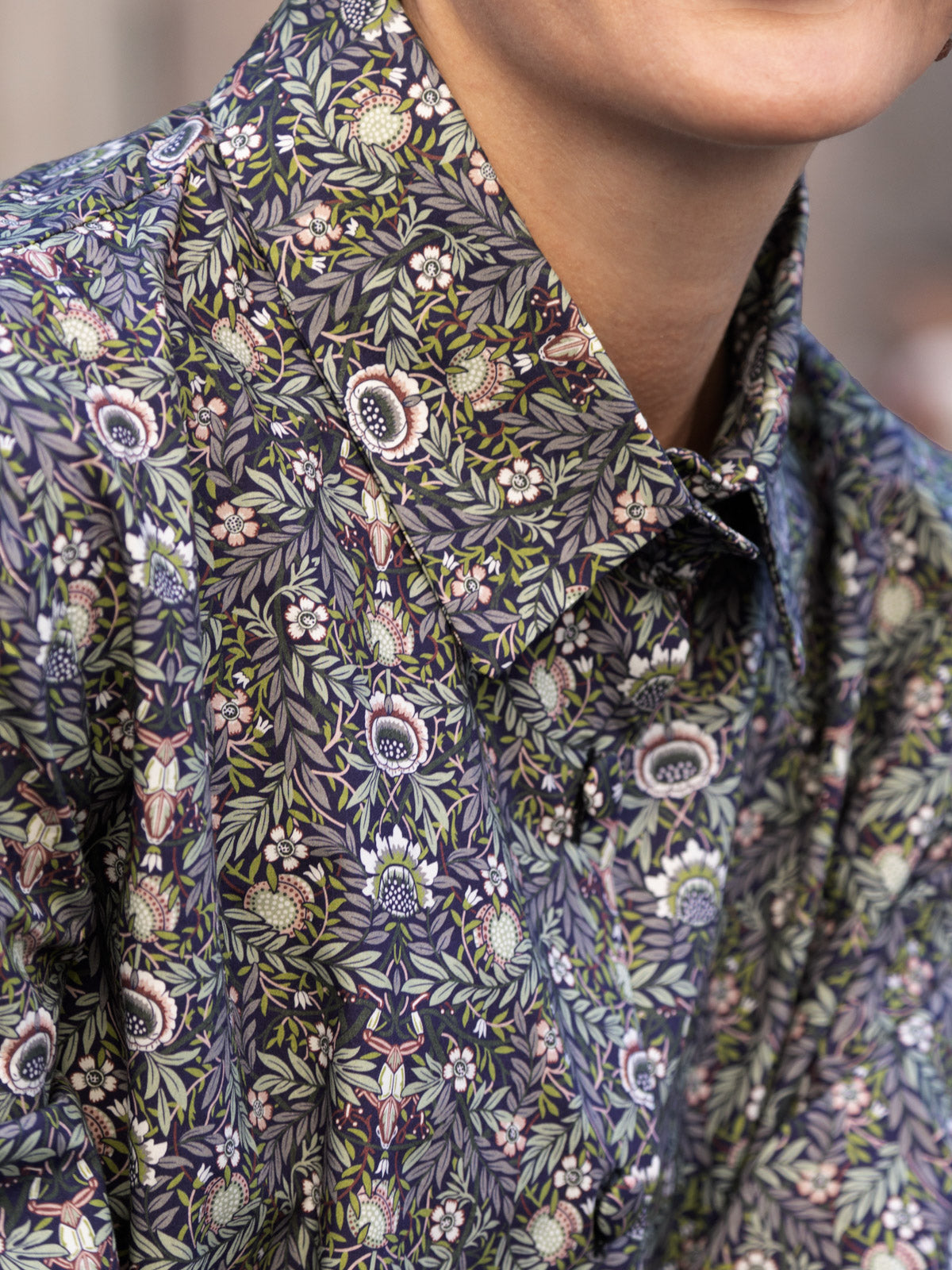 Abito lungo Liberty cotone: dettaglio della camicia con stampa Liberty su fondo scuro, con foglie e fiori.