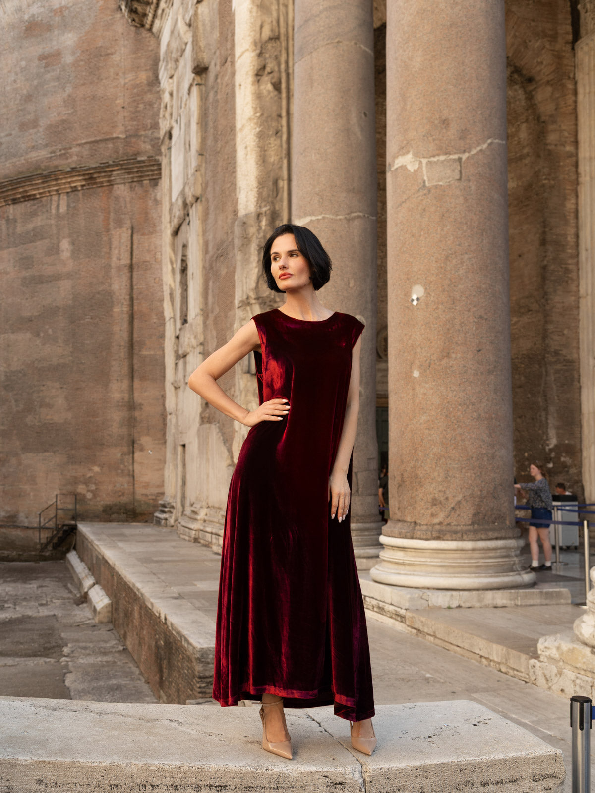 Abito di velluto di seta elegante Livia in tonalità borgogna indossato davanti a monumenti storici.