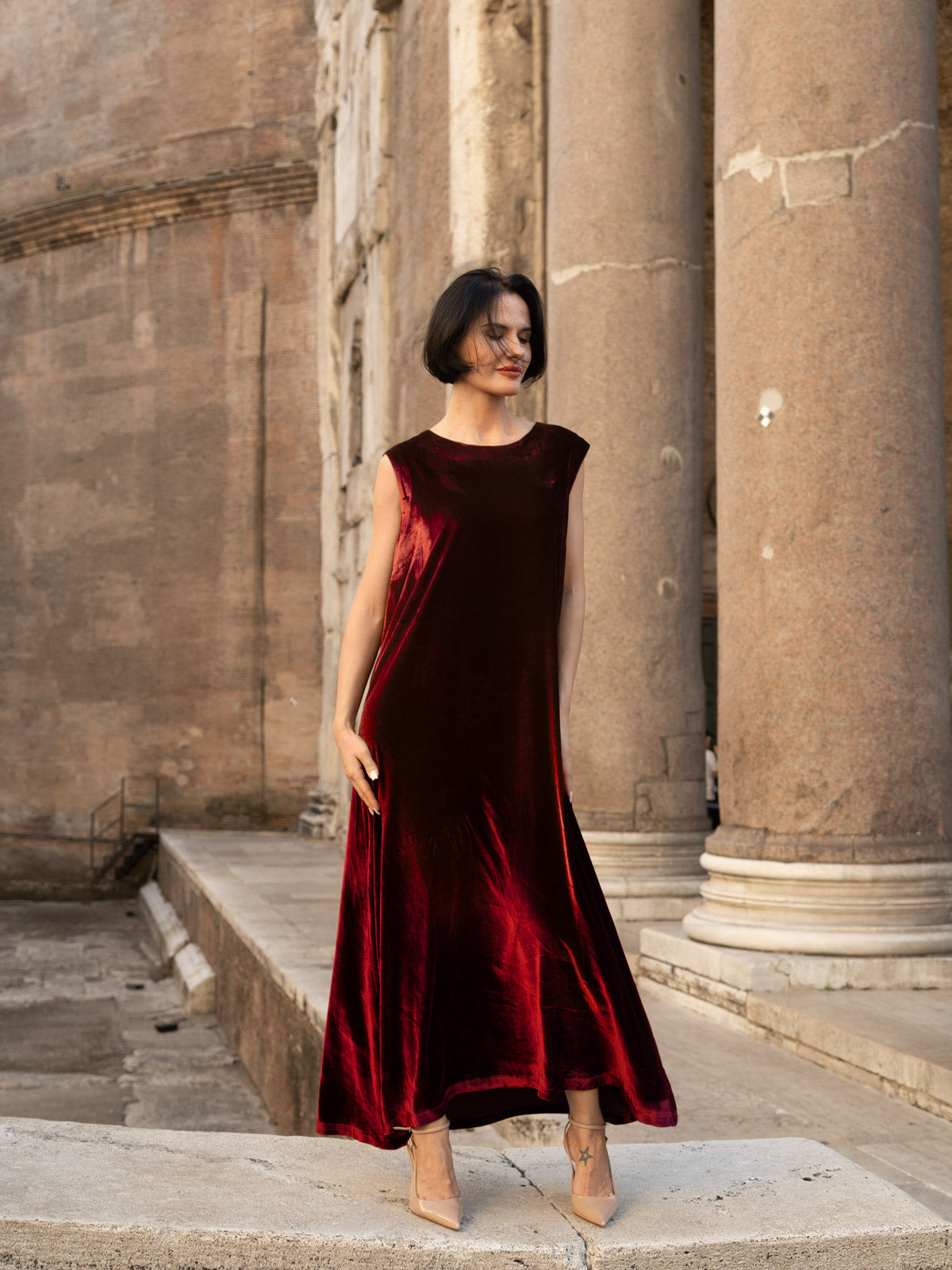 Abito di velluto di seta elegante indossato da una donna in un contesto storico, tonalità borgogna lucida.